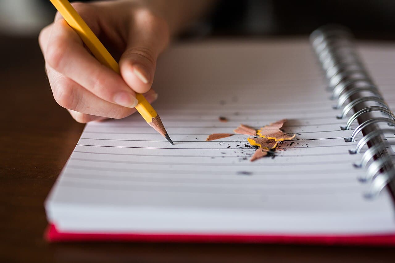 Mano escribiendo con un lápiz en un cuaderno